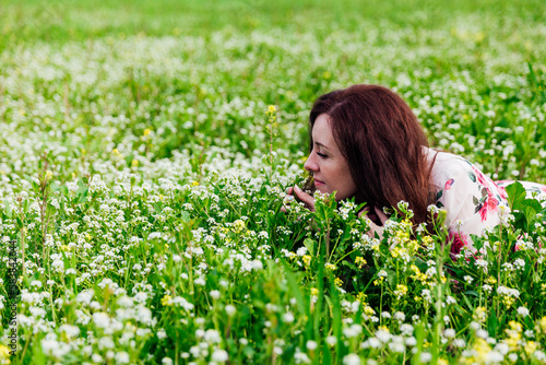 a woman smells flowers in a green clearing