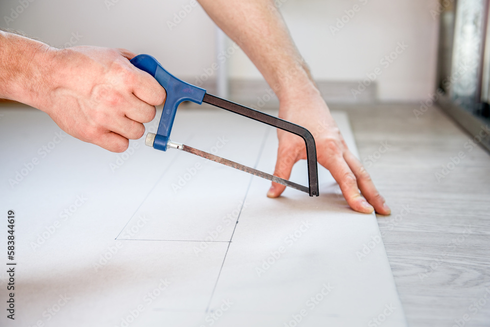 a man saws off drywall for an interior wall with a saw. Diy - obrazy, fototapety, plakaty 