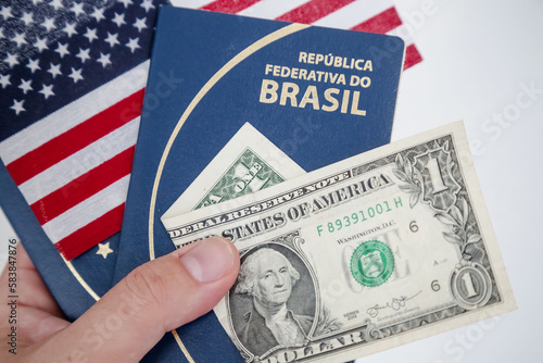 Dolares com passaporte brasileiro na mão de uma pessoa indo viajar.