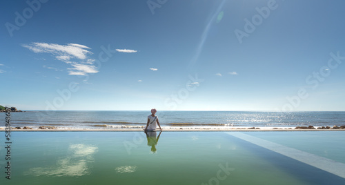 A female tourist is excited at the infinity pool overlooking the sea at the four-star Quynh Vien Resort, Ha Tinh provice, Vietnam photo