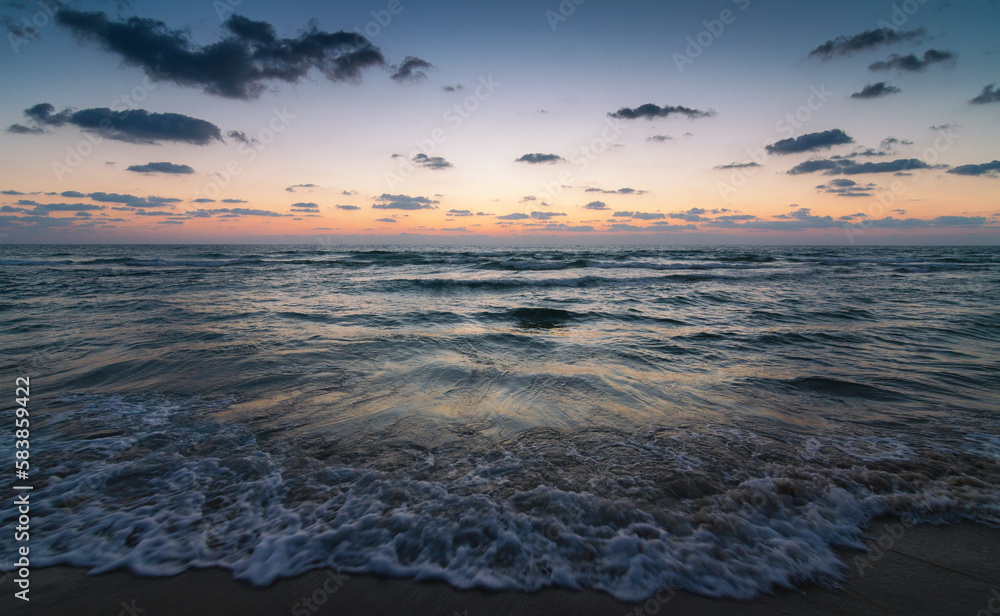 Sunset over the sandy beach of Mediterranean sea in Israel