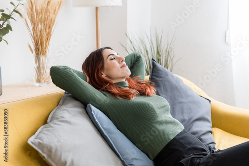 Dreamy woman resting on sofa in living room