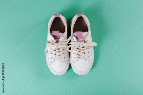 Kids white sneakers. Color background. Fashion kids outfit. Children's clothes and accessories for spring, autumn or summer. Flatlay, top view.