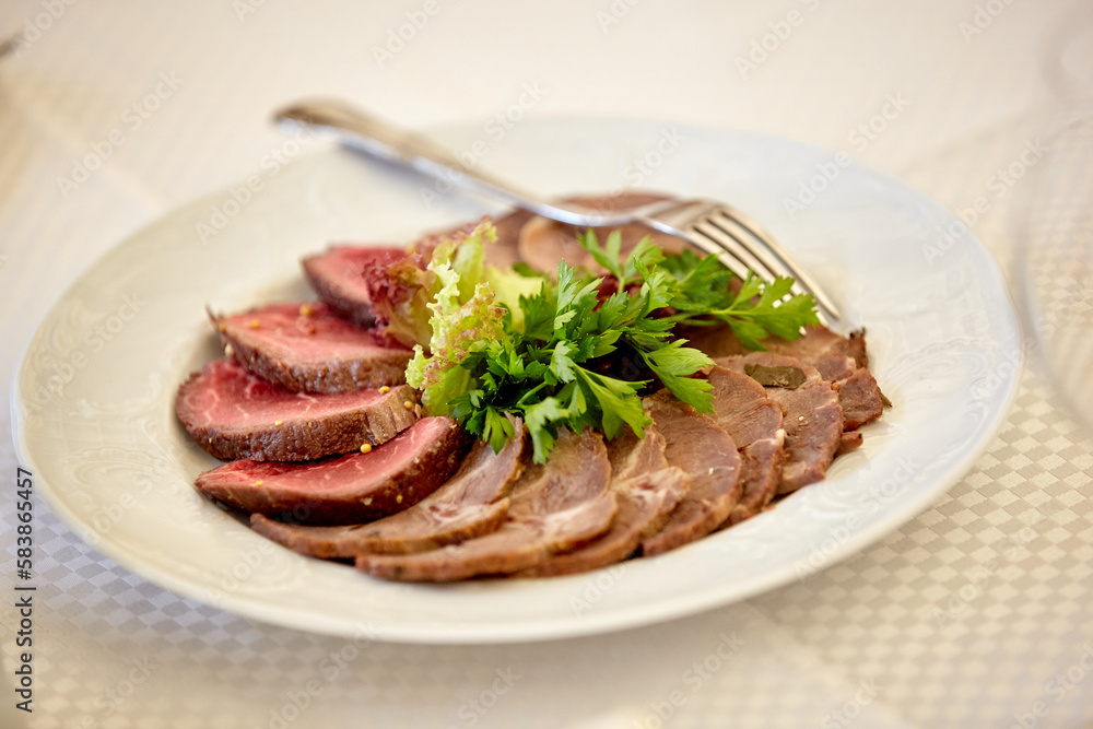 Appetizer plate with a meat selection. Sliced baked ham. Table setting in a restaurant