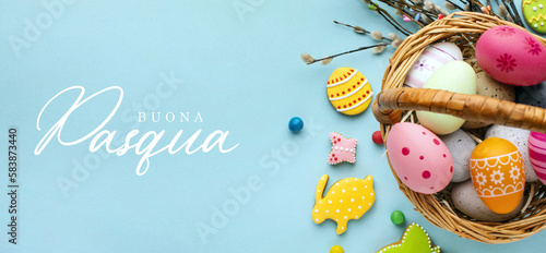 Buona Pasqua. Lettering in lingua italiana su sfondo azzurro. Immagine di un cesto pieno di uova pasquali decorate. 