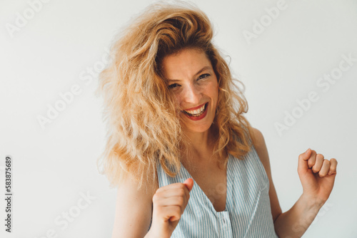 Playful young woman with curly hair dancing with her hands, waist up portrait on white background