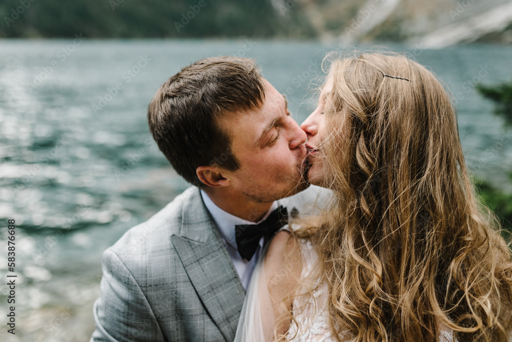 The bride and groom near the lake in the mountains. Newlyweds together against the backdrop of a mountain landscape. Romantic wedding couple in love. Scenic mountain view. The bride and groom near the lake in the mountains. Newlyweds together against the backdrop of a mountain landscape. Romantic wedding couple in love. Scenic mountain view.