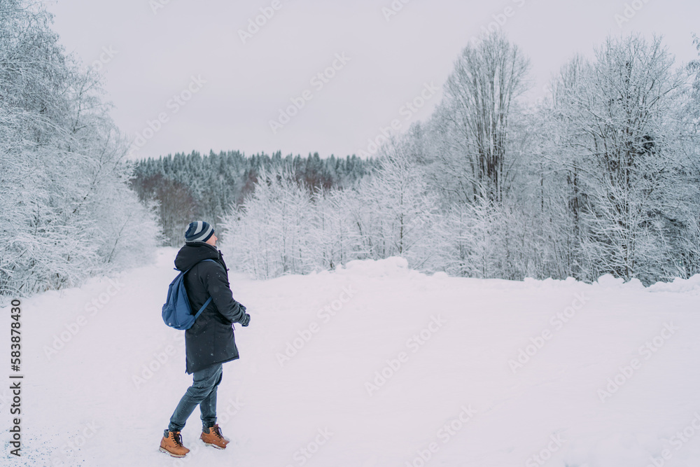 A man with a blue backpack in a snowy park