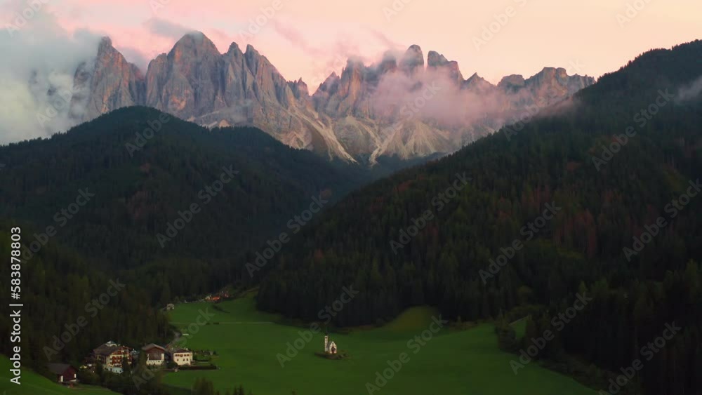 Aerial view of Val di Funes valley with amazing alpine Dolomites covered with pink clouds at sunset. Aerial view of Val di Funes valley with amazing alpine Dolomites covered with pink clouds at sunset.