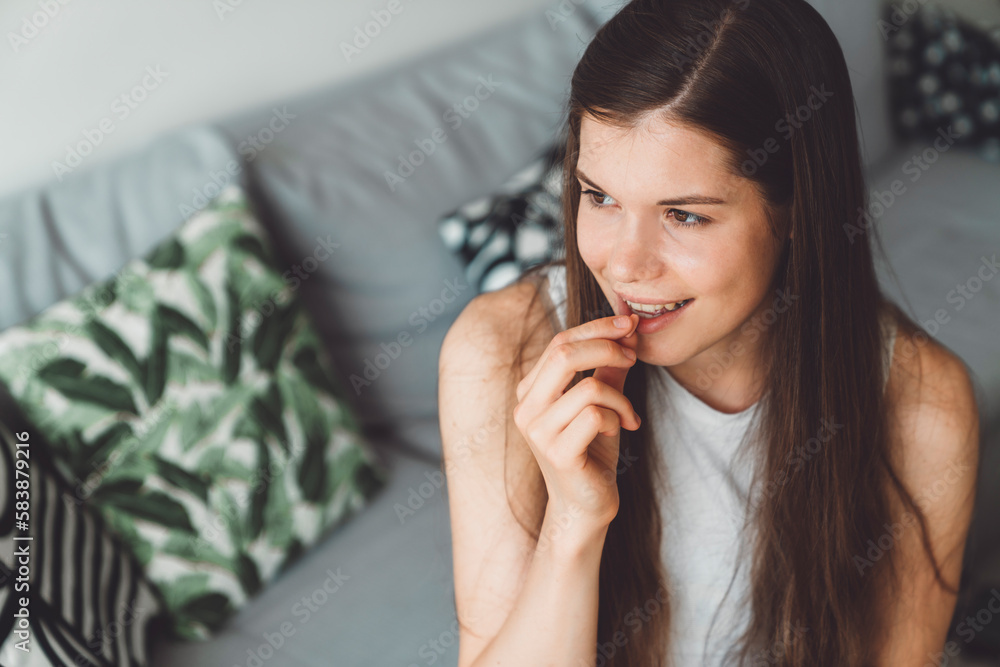 Smiling young woman, waist up portrait, taking her supplements while sitting on the couch at home Smiling young woman, waist up portrait, taking her supplements while sitting on the couch at home