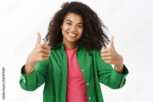 Smiling Black woman shows thumbs up, like and recommend smth, say yes, nod in approval