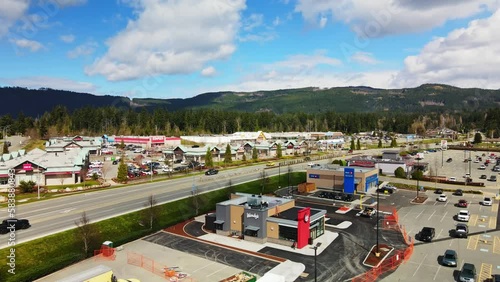 Cars Driving In The Road Passing By Fast Food Restaurant Chain In Port Alberni, BC, Canada. - aerial photo