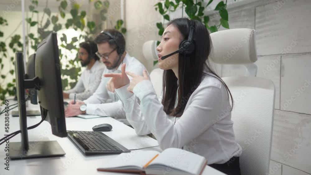 Side-view portrait young beautiful qualified female operator working in customer support sphere with colleagues. Teamwork of multiethnic group of professional employees using computers and headphones. Side-view portrait young beautiful qualified female operator working in customer support sphere with colleagues. Teamwork of multiethnic group of professional employees using computers and headphones.