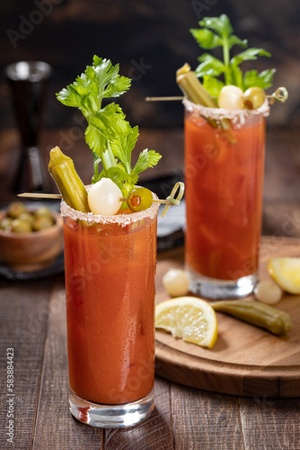Bloody mary cocktail with garnishes on dark wooden background