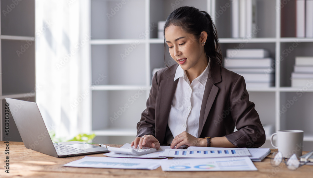 Business Asian woman working at office with documents on her desk, calculator to calculate planning analyzing the financial report, business plan investment, finance analysis concept Business Asian woman working at office with documents on her desk, calculator to calculate planning analyzing the financial report, business plan investment, finance analysis concept