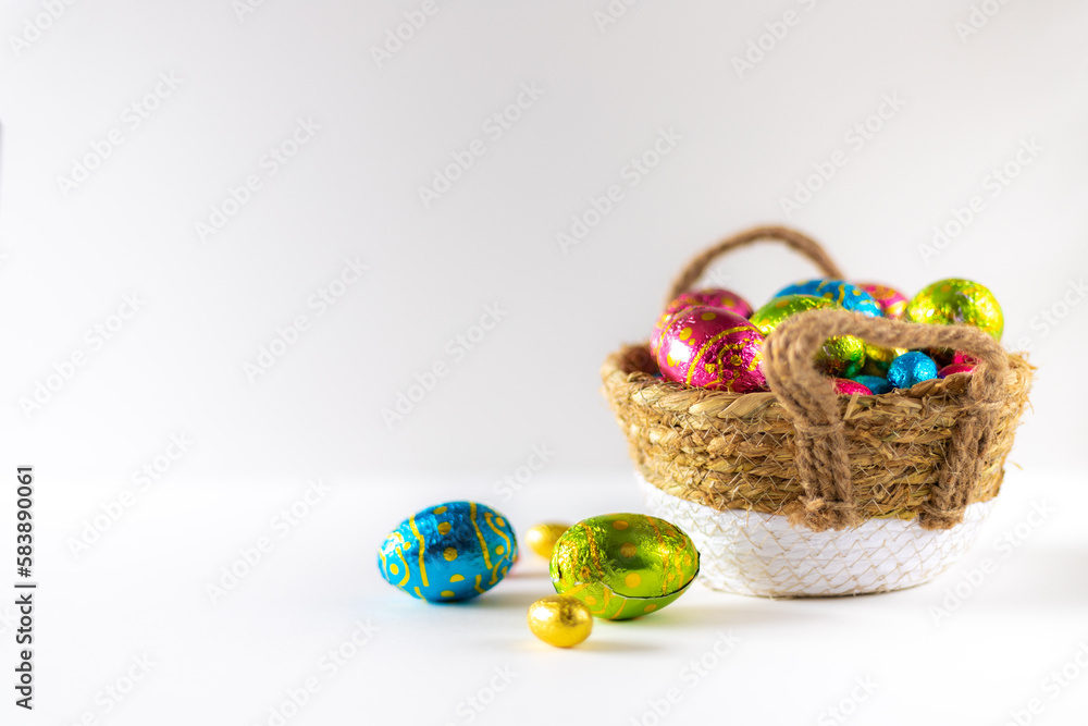Easter eggs in basket with white background on white table. Studio lighting colorful easter decorated eggs for egg hunt with wicker basket and flowers. Banner for web and composition. Wishes card Easter eggs in basket with white background on white table. Studio lighting colorful easter decorated eggs for egg hunt with wicker basket and flowers. Banner for web and composition. Wishes card