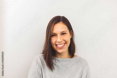 Waist up portrait of cheerful young woman with shoulder length hair and big white smile on white background 