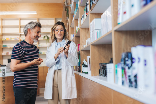 Pharmacist showing a man a skincare product in a chemist