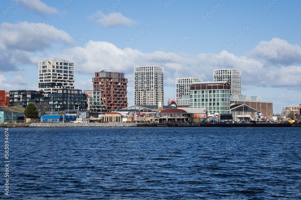 Obraz premium Panoramic view from the IJ river to NDSM neighborhood (Amsterdam-Noord borough), located on the former terrain NDSM-wharf, along the IJ river. AMSTERDAM, The NETHERLANDS.