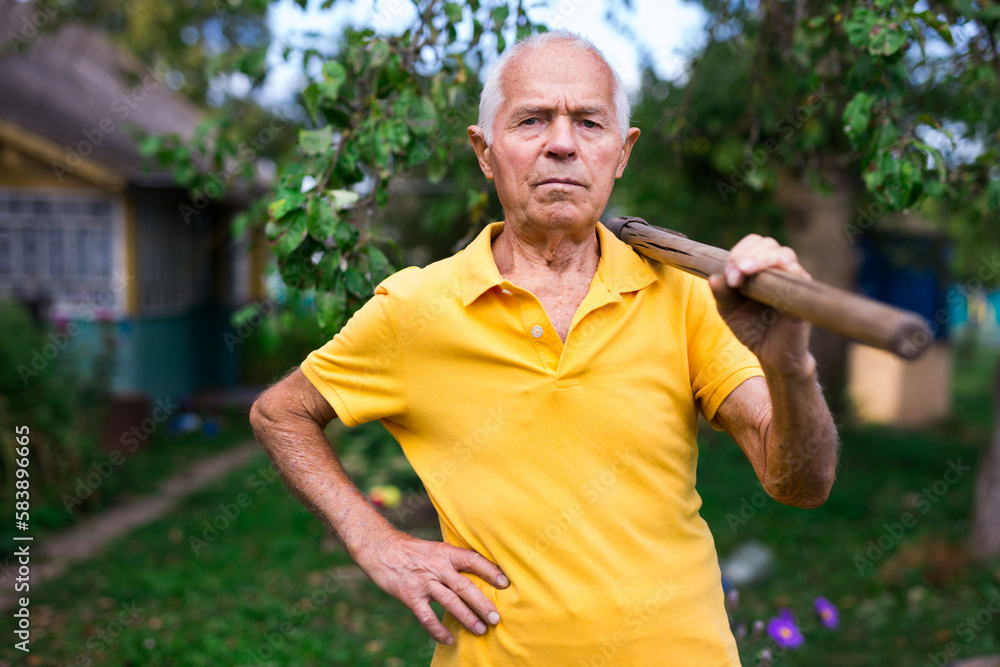 Obraz premium Old man standing in backyard with shovel in hand