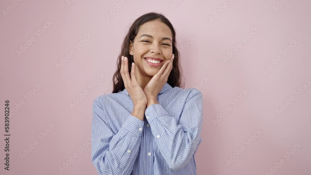 Young beautiful hispanic woman touching face with hands over isolated pink background Young beautiful hispanic woman touching face with hands over isolated pink background