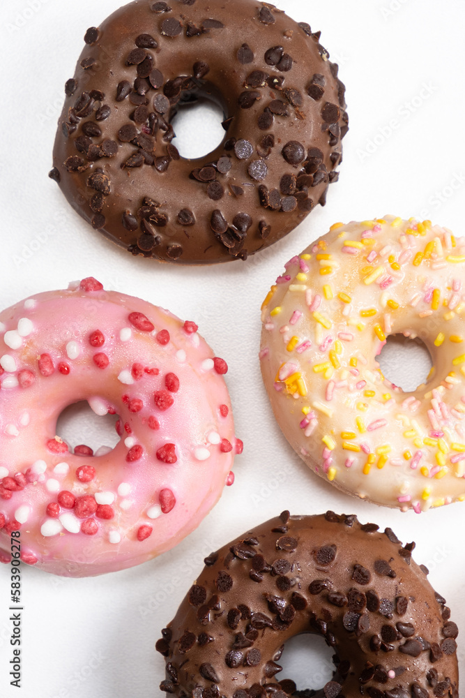 Lots of little donuts with white, pink and chocolate glaze on a white background, top view Lots of little donuts with white, pink and chocolate glaze on a white background, top view