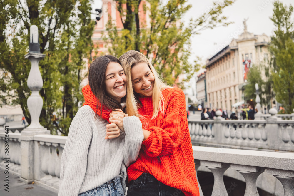 Sister hugging while walking on the city streets, having a day off to spend together 