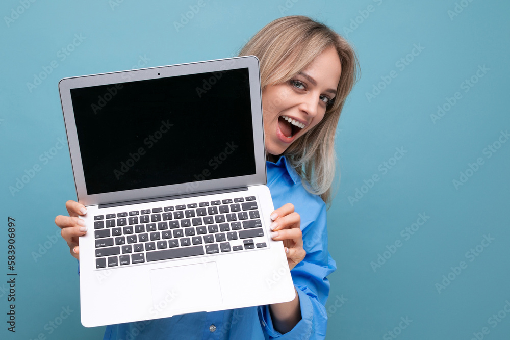 happy lucky blonde girl rejoices with a laptop in her hands with an empty space for a web page on a blue background happy lucky blonde girl rejoices with a laptop in her hands with an empty space for a web page on a blue background