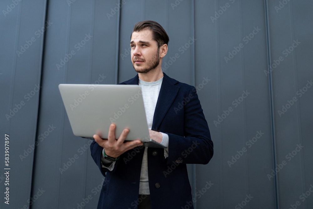 successful young architect holding a laptop on the background of a business center successful young architect holding a laptop on the background of a business center