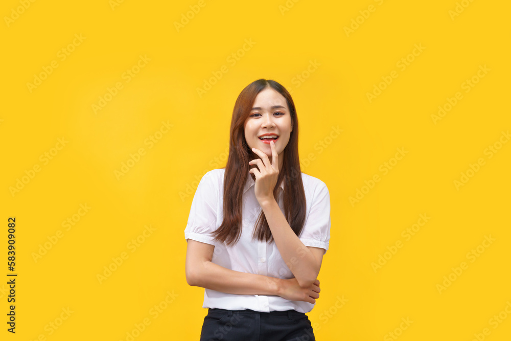 Women are smiling while use hand to touching mouth and crossed arm isolated on yellow background Women are smiling while use hand to touching mouth and crossed arm isolated on yellow background