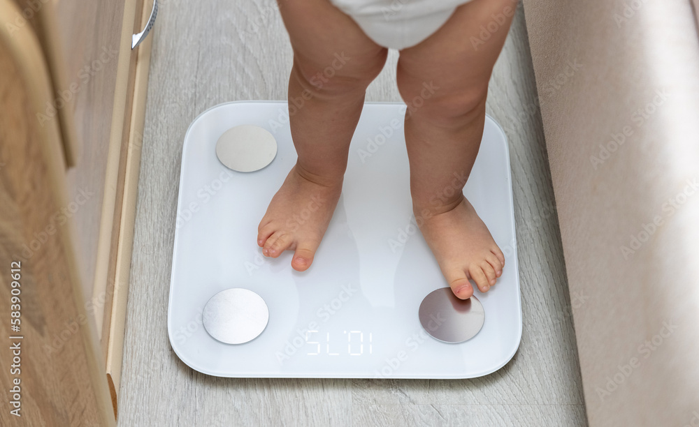 baby legs barefoot feet on body composition scale measuring weight home