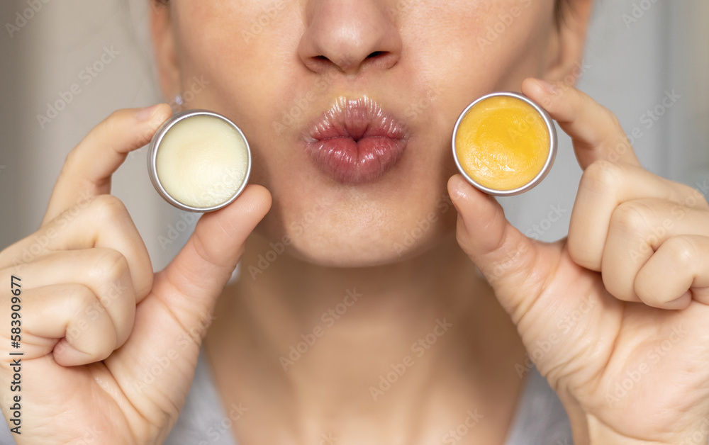 woman applying on lips balm or scrub from natural ingredients half bottom face kissing gesture smiling female.scrub and lip balm from small jars girl taking with finger rotation moves coconut oil - obrazy, fototapety, plakaty 