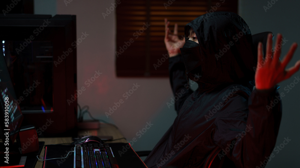 Hacker in hoodie raising hands while having problem with hacking programming system or server Hacker in hoodie raising hands while having problem with hacking programming system or server