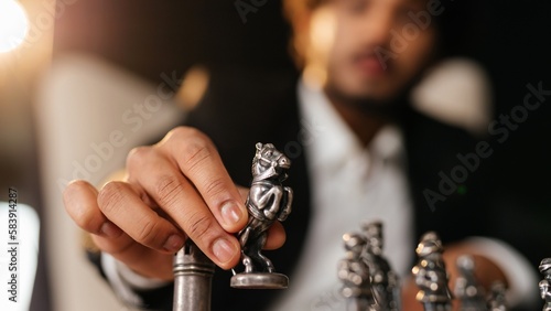 Cropped view of a chess player holding a chess piece in his hand. Selective focus of businessman moving a knight chess figure. Business tactis, business strategy concept