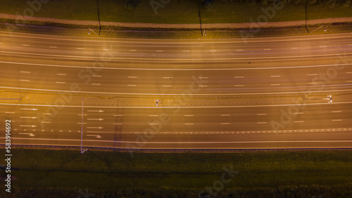 Aerial down view of the bigger highway with many cars next to forest and the historical and at same time modern city of St. Petersburg at light summer night, fog