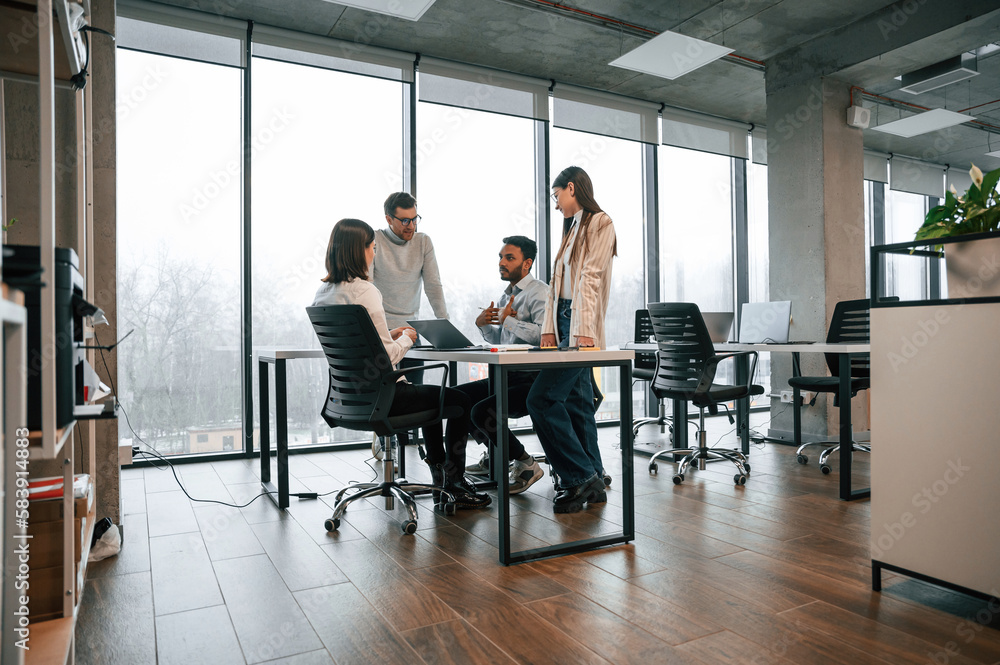 Against big windows by the table. Four people are working in the office together Against big windows by the table. Four people are working in the office together