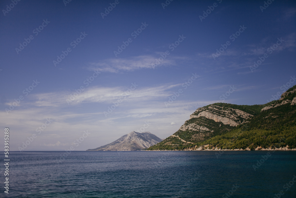 Landscape of the Adriatic Sea, mountains with clouds, sky, rocks on a sunny day. Dalmatia, Croatia.