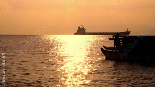 Boat crossing the horizon during dawn, golden hour