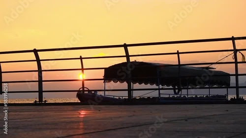 Docked tourist boat seen through rails on the shore during sunset Aqaba Jordan