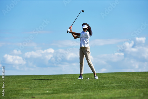 Minimal full length portrait of sporty young woman playing golf on green field against sky and swinging golf club with precision, copy space