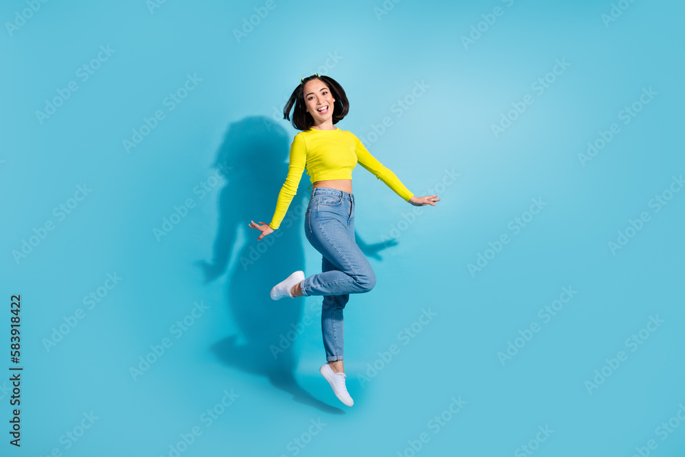 Full size photo of excited pretty girl jumping good mood empty space isolated on blue color background Full size photo of excited pretty girl jumping good mood empty space isolated on blue color background