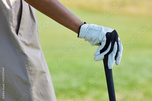 Close up of gloved female hand holding golf club outdoors against green field, copy space