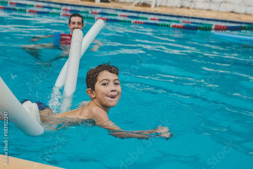 Fototapeta Naklejka Na Ścianę i Meble -  Menino na piscina nadando com o pai