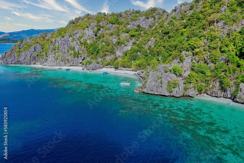 Panorama drone shot of majestic rocks in Coron  Palawan in the Philippines  covered with bushes and surrounded by the sea.