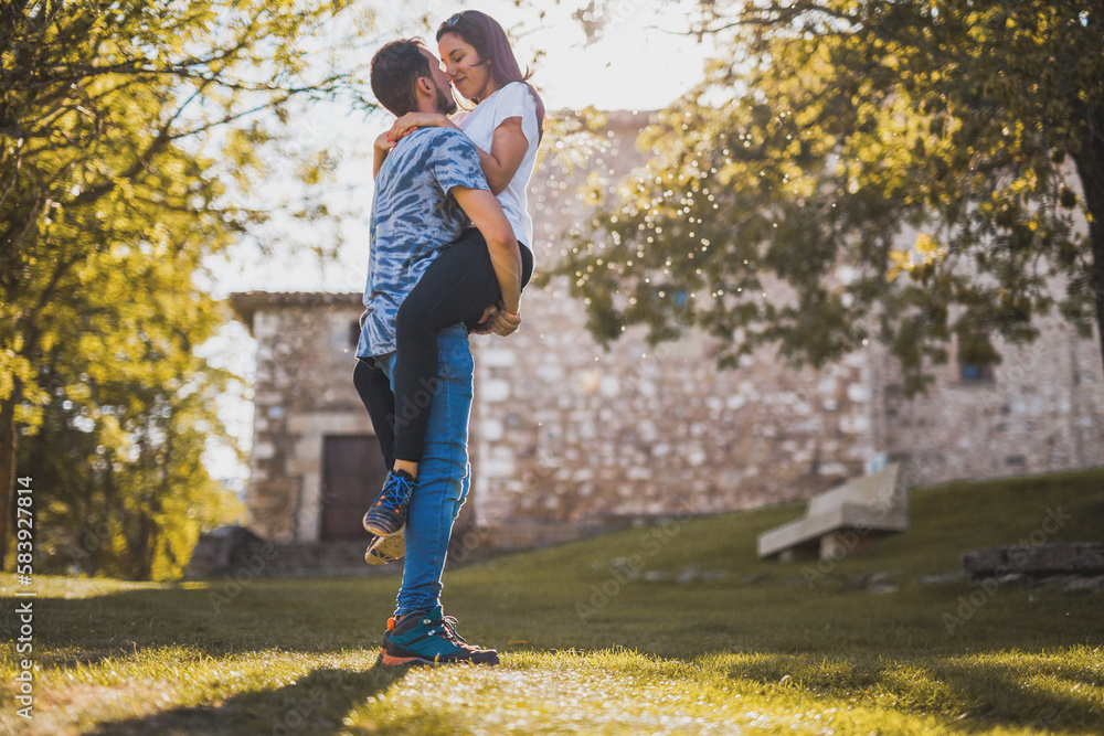 Man carrying girlfriend in park on sunny day Man carrying girlfriend in park on sunny day