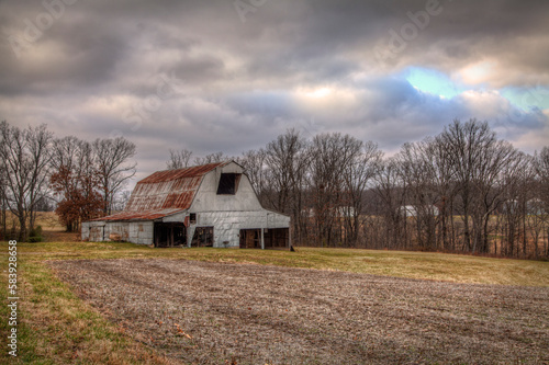 Barn with Many Doors. Barn in a winter field with all the barn doors open. A neatly trimmed field with summers crops removed. Not much happen on a farm in the winter months. 