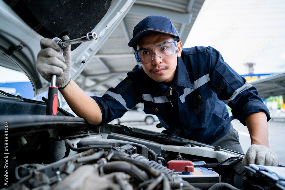 Portrait of an Asian mechanic checking the safety of a car. Maintenance of damaged parts in the garage. Maintenance repairs. Repair service concept. Portrait of an Asian mechanic checking the safety of a car. Maintenance of damaged parts in the garage. Maintenance repairs. Repair service concept.