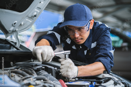 Portrait of an Asian mechanic checking the safety of a car. Maintenance of damaged parts in the garage. Maintenance repairs. Repair service concept.