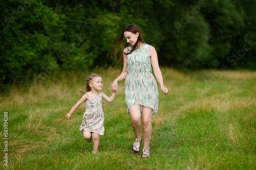 Portraits of joyful mother and daughter spend time together, enjoy happy family time, run in the park. The concept of a happy family, family day,mother's day, countryside vacation, unity with nature.