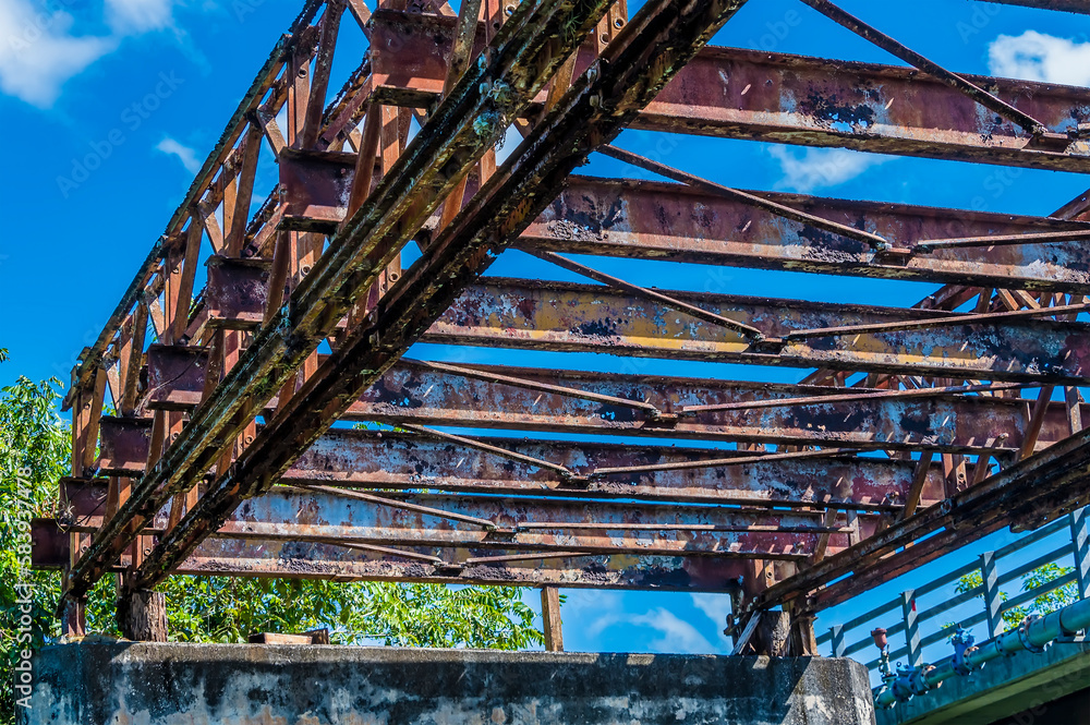 A view underneath an abandoned bridge over the Belize River in Belize on a sunny day
